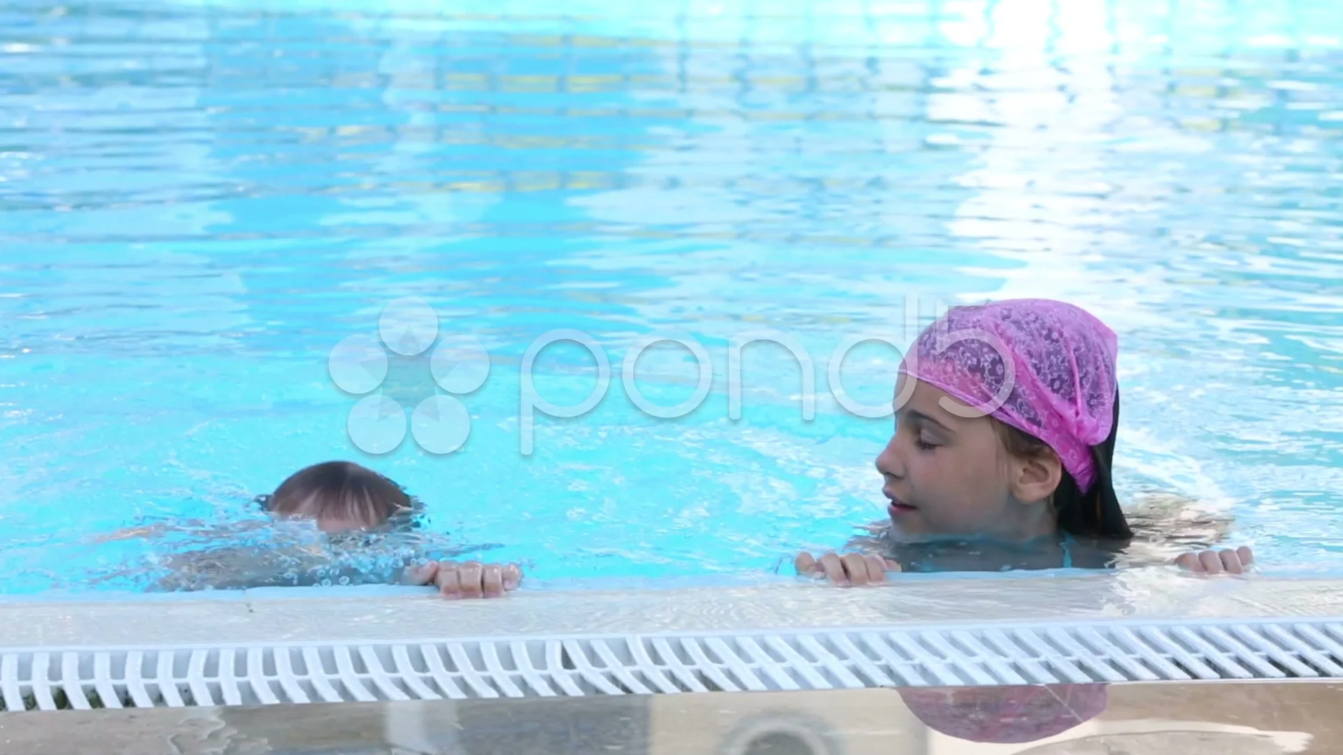 Brother and sister in the pool dive under the water in turn