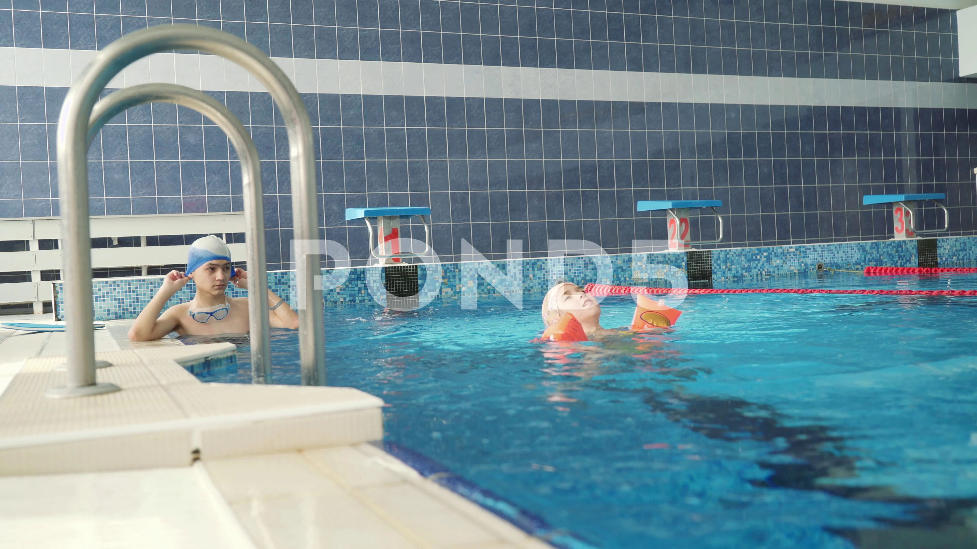 Brother and sister swim in the indoor pool. 4k