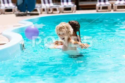 Brother laughing while playing ball with sister in pool Stock Photos