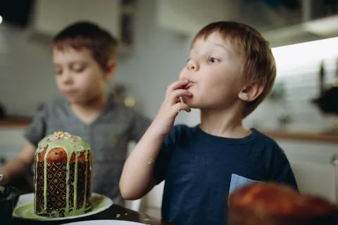 Brothers decorating Easter cakes with glace icing eating sugar topping. Image 스톡 사진