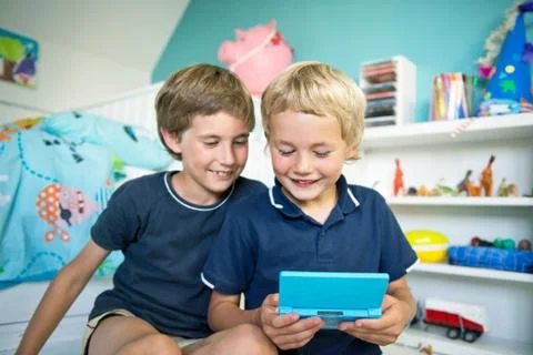 Brothers with handheld computer game Stock Photos