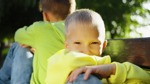 Brothers Sitting Back-to-Back on Park Bench Stock Footage 279911949