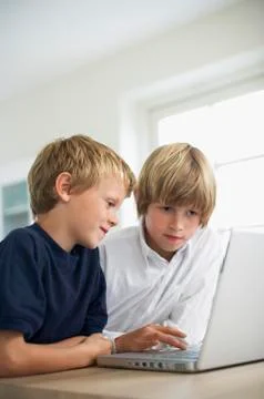 Brothers Using Laptop On Table 写真素材