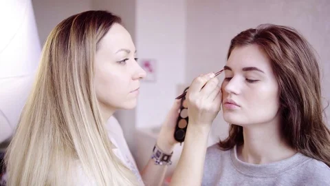 Brow master paints model's eyebrow Stock Footage 82466450