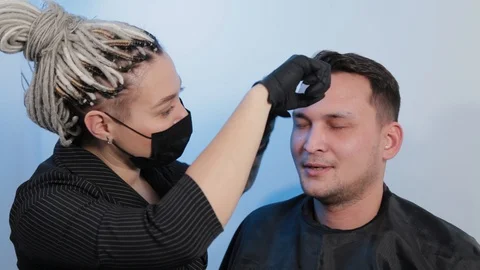 Browist makes eyebrow correction with a thread to a man in a beauty salon. Stock Footage 130082899