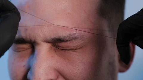 Browist makes eyebrow correction with a thread to a man in a beauty salon. Stock Footage 130082989