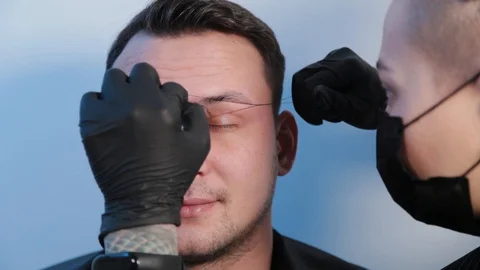 Browist makes eyebrow correction with a thread to a man in a beauty salon. Stock Footage 130083387