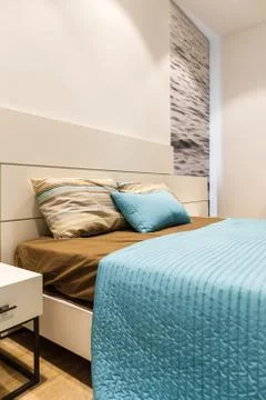 Brown and blue bedclothes on bed in modern bedroom Stock Photos