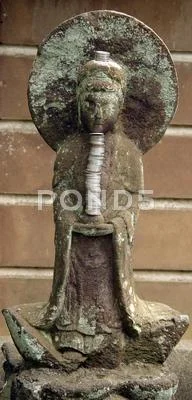 Brown and grey carved stone Buddha with a stack of coins and a large halo