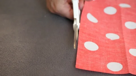 Brown and polka dot material is cut with scissors 動画素材 129517346