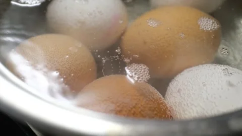 Brown and white chicken eggs boiling in hot water inside a stainless steel pot Stock Footage 319633105