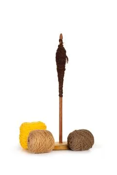 Brown and yellow wool spools and a spindle on white background Foto stock