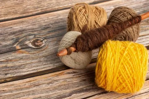 Brown and yellow wool spools and a spindle on a wooden background Stock Photos