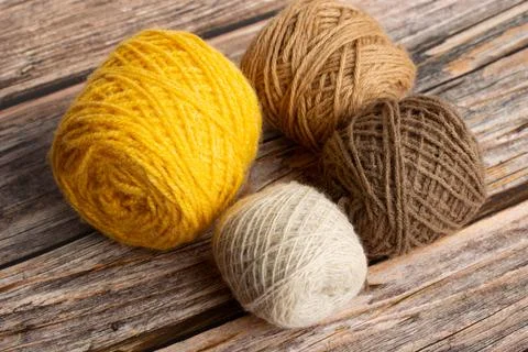 Brown and yellow wool spools on a wooden background Foto stock