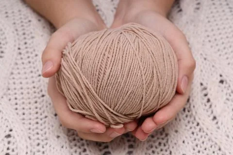 Brown ball of wool in hands on the background of a white knitted tablecloth Stock Photos