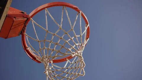 Brown basketball ball fall through basket with net on sunny summer day close up Stock Footage 240053598