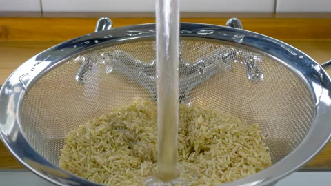 Brown basmati rice being washed under a running tap. Video stock 180870971