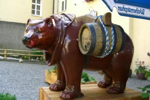 Brown bear sculpture in front of a brewery dressed like a monk with beer barrels 写真素材