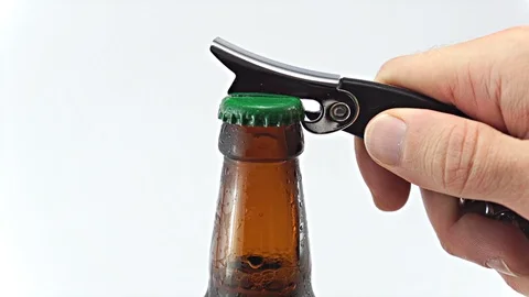 Brown beer bottle being Uncapped by male hand using chromed metal bottle opener Stock Footage 123009170