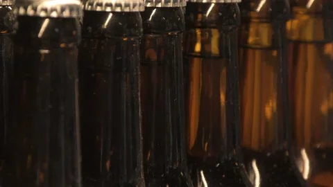 Brown beer bottles with closed lids stand in a row on the bar counter, Stock Footage 157229717