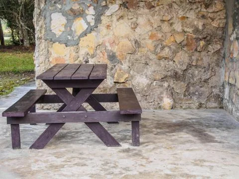Brown bench in front of a stone wall. Stock Photos