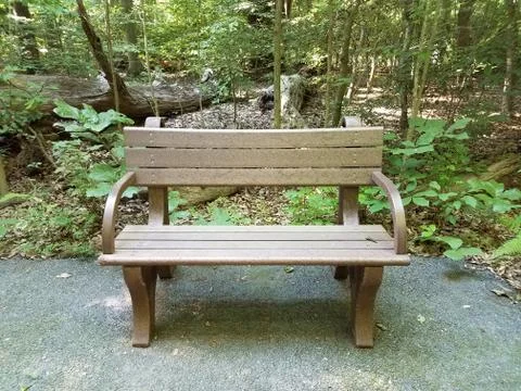 Brown bench on pebbles in the forest Stock Photos