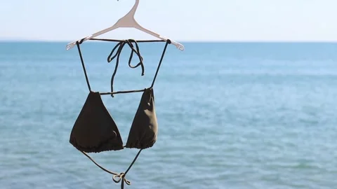 Brown bikini swimsuit close-up on the background of blurred blue sea Stock Footage 343499789