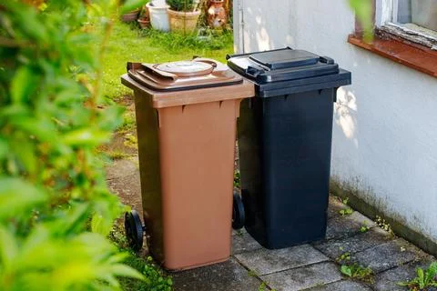 Brown bio waste bin and black residual waste bin standing side by side for re Stock Photos