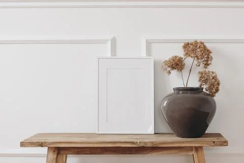 Brown bold vase. Dry hydrangea flowers on old wooden bench. Blank black picture Fotos Stock