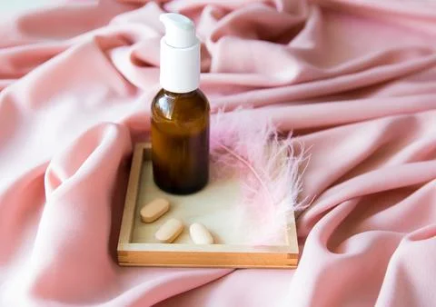 Brown bottle, tablets and feather on the texture table. Stock Photos