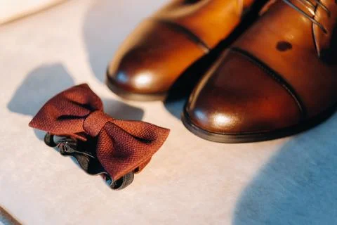 Brown bow tie on a light background and boots. Stock Photos