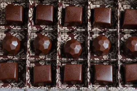 Brown box closeup with several chocolate candies. Stock Photos