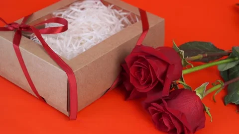 Brown box with a gift and red roses on a red background. Stock Footage 169598506