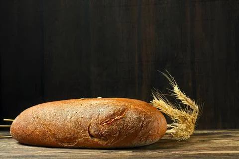 Brown bread and rye ears on a wooden table 写真素材