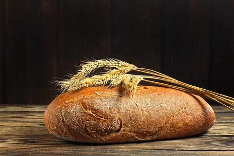 Brown bread and rye ears on a wooden table Stock Photos