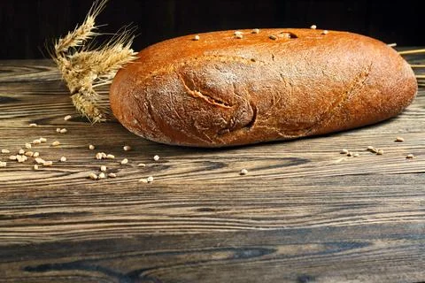 Brown bread and rye ears on a wooden table Stock-Fotos