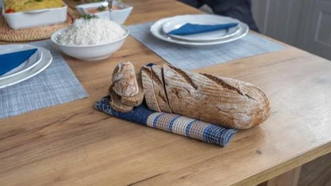 Brown bread on a blue cloth with plates in background Stock Photos