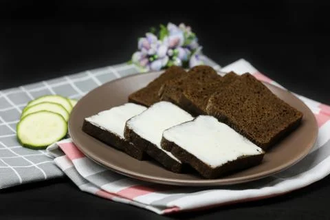 Brown bread with processed cheese on a plate and towels isolated on black Stock Photos