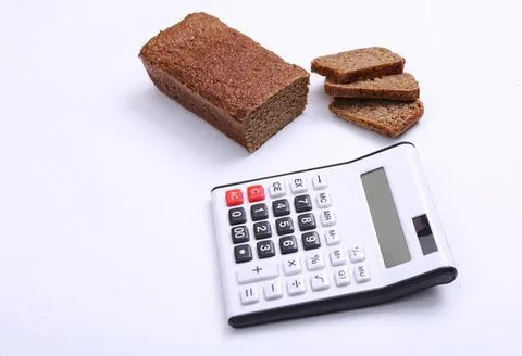 Brown bread slices next to calculator on white background Stock Photos