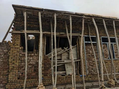 Brown Brick Building Under Construction with Wooden Supports 스톡 사진