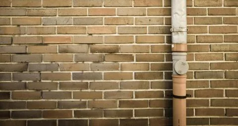 Brown brick wall with drainpipe on the right side of frame background Stock Photos