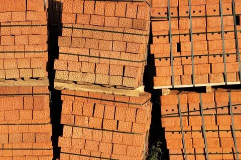 Brown bricks stacked on pallets along construction site fence 写真素材