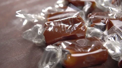 Brown candy toffees in a wrapper on a wooden rustic background. Sweet xmas ta Stock Footage 169019879