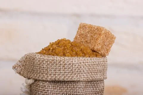 Brown cane sugar in a bag with a cube of shed on top Foto stock