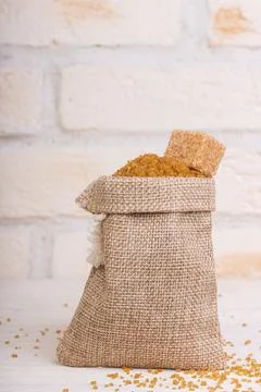 Brown cane sugar in a bag with a cube of shed on top Stock Photos