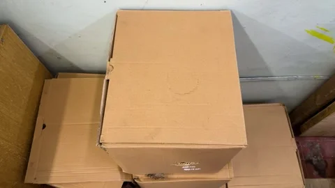 Brown cardboard boxes stacked in corner near white wall for storage  Video stock 342438273
