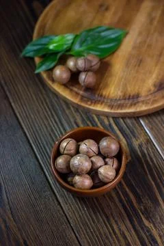 Brown ceramic bowl with macadamia nuts inside. Stock Photos
