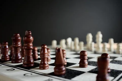 Brown chess pieces facing white pieces on chessboard Stock Photos
