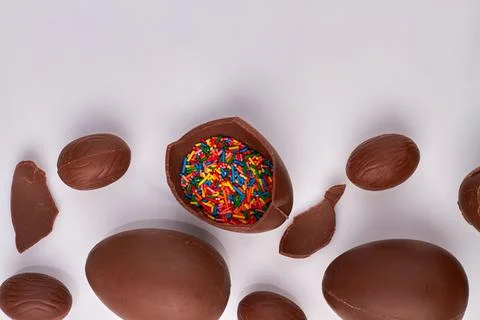 Brown choco egg filled with rainbow sprinkles. Stock Photos
