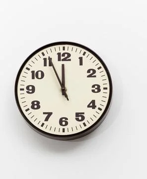 Brown clock on white office wall near noon Brown simple plastic wall clock... Stock Photos